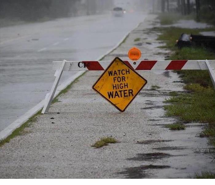broken down high water sign in front of a road that has lots of water