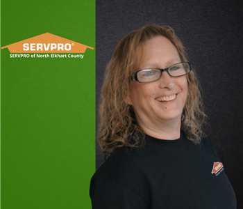 Woman smiling at the camera with a green and black background and a servpro logo