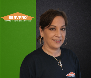 Woman smiling at camera with green and black background and servpro logo 