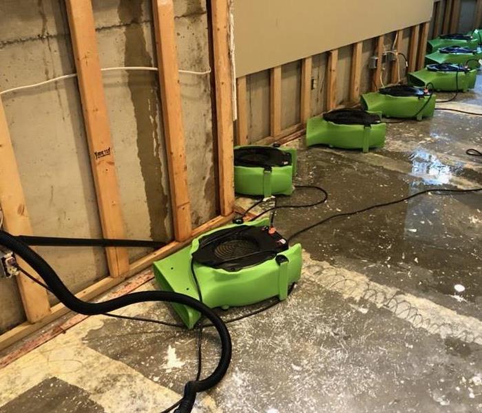 a room with flood cuts in the wall and servpro air movers drying out the wetness 